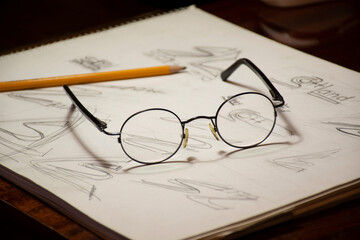 Fototapeta premium glasses and pencil lie on the sketch.