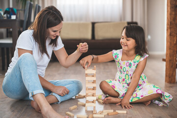 Young mother with her little daughter play game in wood block