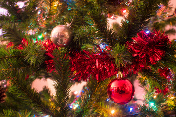 Bolas decorativas, luces y guirnaldas adornando un árbol de Navidad.