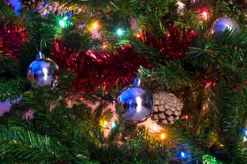 Bolas decorativas, guirnaldas y luces en un árbol de Navidad.