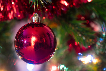 Bola decorativa roja y guirnaldas para adornar el árbol de navidad.