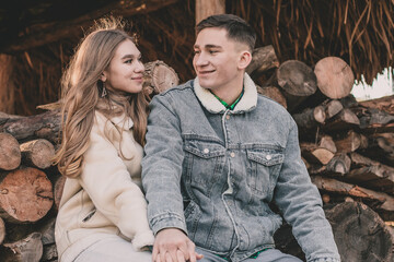 
A guy and a girl are sitting in a gazebo against the background of neatly folded firewood in...