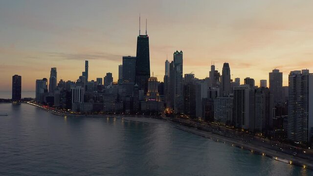 Flying above Lake Michigan with beautiful view of Chicago downtown skyline at sunset.