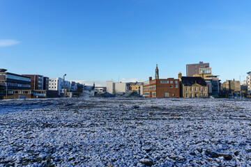 Low view of ice covered ground and city buildings in the background
