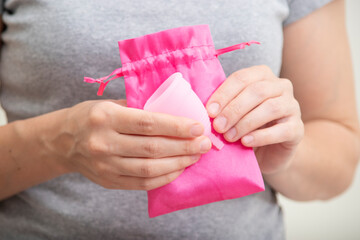 Young woman hands holding menstrual cup and small bag. menstrual cup in female hands