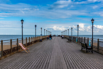 A view along Skegness pier, UK with a modern wind farm just visible on the horizon on a bright autumn afternoon