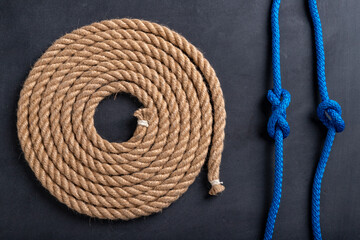 A rope coiled in a circle and two sailing knots. Accessories for sea wolves on the table.