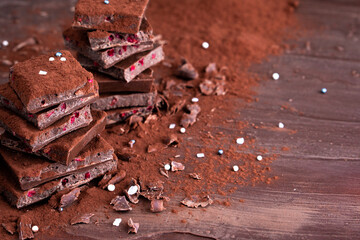 Organic food snack tasty sweet dessert milk dark chocolate bar macro closeup broken slide piece and fruit orange raspberry hazelnut nuts on cocoa cacao powder wooden table for new year Christmas gift