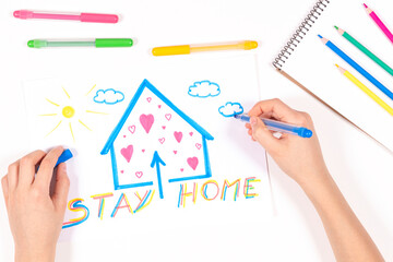 Stay at home. Kid hands drawing picture with house and message Stay home. Top view. Quarantine...