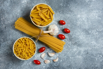 Fototapeta na wymiar Raw pasta with fresh vegetables on a gray background