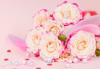 delicate bouquet of bushy peony roses with bright ribbons, pearls, feathers and hearts  on a pink background, the concept of congratulations on Valentine's day