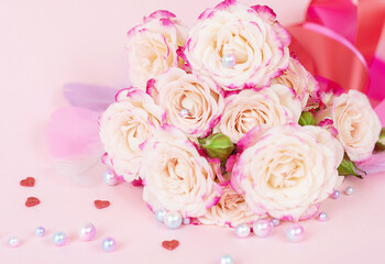 delicate bouquet of bushy peony roses with bright ribbons, pearls, feathers and hearts  on a pink background, the concept of congratulations on Valentine's day
