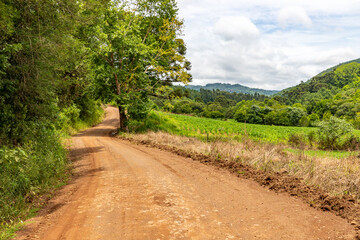 Fototapeta na wymiar Dirty road, farm field and forest in Morro do Xaxim mountain