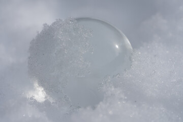 Glass ball in snow covered with ice and snow flakes