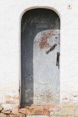 Closed gray steel door in an old white stone wall