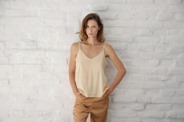 Indoor fashion portrait of Caucasian woman in beige silk outfit
