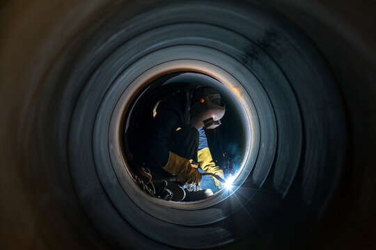 Welder is welding in the spiral welded large pipe. The spiralweld manufacturing process is one of the most cost effective ways to produce steel pipe. Spiralweld pipe is manufactured from steel coil.