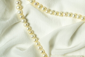 Natural silk draped fabric with pearl beads. Elegant romantic background.