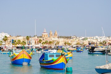 Fototapeta na wymiar Maltese boats float in the harbor of Marsaxlokk, Malta. the fishing boats are decorated with the eye of Osiris to keep the fishers safe at sea.