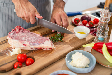 A close-up of the chef's hands cutting rosemary on a wooden board