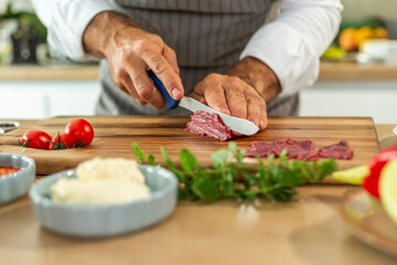 A close-up of the chef's hands cutting carpaccio