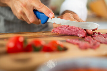 A close-up of the chef's hands cutting carpaccio