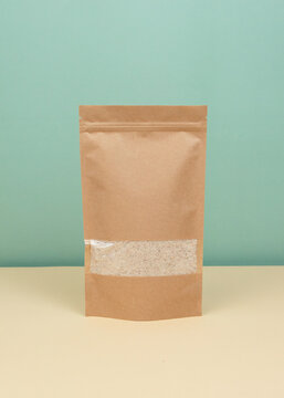Brown kraft paper doypack bags with groceries front view on a yellow background. Packaging for foods and goods template mock-up. Packs with windows for weight products.