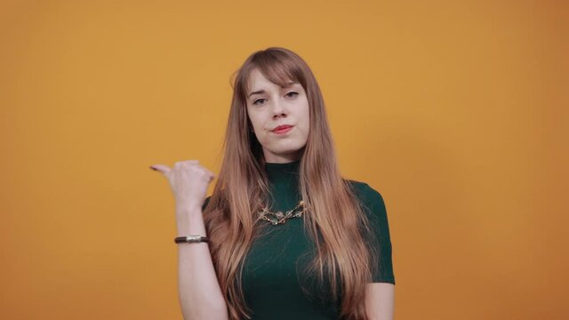 Pointing thumb over shoulder at blank space isolated. Astonished points with thumb aside. Look here. Studio photo portrait of satisfied sure, recommending cheerful nice human offering new solution