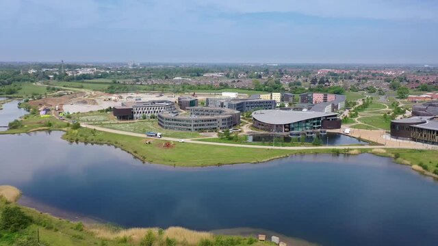 Aerial footage of the University of York, Campus East buildings in the City of York in North Yorkshire in the UK along side a lake on a sunny summers day taken with a drone along side the river