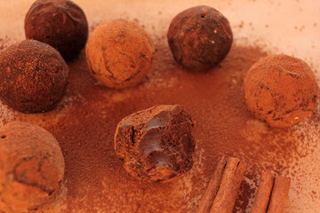 Chocolate truffles, cocoa powder and cinnamon sticks on a craft paper background. View from overhead 