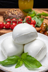 Cheese collection, white balls of soft Italian cheese mozzarella, served with red cherry tomatoes, fresh basil leaves