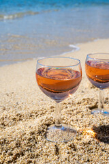 Two glasses of local rose wine on white sandy beach and blue Mediterranean sea on background, near Le Lavandou, Provence, France