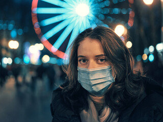 Woman in medical mask against the background of city lights