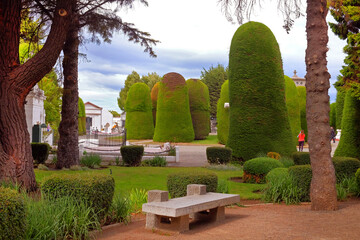 Cemetery of Punta Arenas, with beautiful green garden decoration, against a blue sky covered by white clouds.