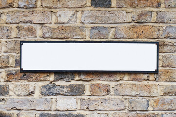 Cartel  o placa con espacio en blanco para escribir sobre pared de ladrillos © Manu
