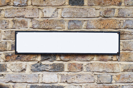 Cartel  o placa con espacio en blanco para escribir sobre pared de ladrillos