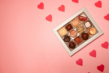 Chocolate candies box. Valentine's day gift. Red hearts paper pattern. Pink background. Copy space