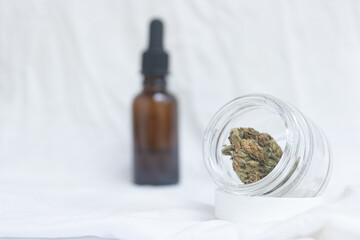 Glass bottle with a bud of cannabis along with a bottle of CBD oil with a dropper on a white background.medical cannabis concept, marijuana oil.