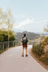 Obraz premium Man standing on a road in the mountains with his backpack.