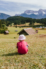 Young girl wearing a hat looking at a beautiful landscape on a sunny day with a mountain range...
