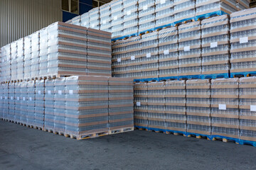 The open air storage and carriage of the finished product at industrial facility. A glass clear bottles for alcoholic or soft drinks beverages and canning jars stacked on pallets for forklift. - 402751283