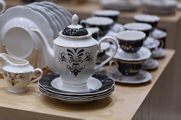 Obraz na płótnie Canvas Creative shot of tea pot and White crockery for tea in shallow depth of field. Cups and saucers on a wooden table. Set cups and teapot in restaurant for event celebration.