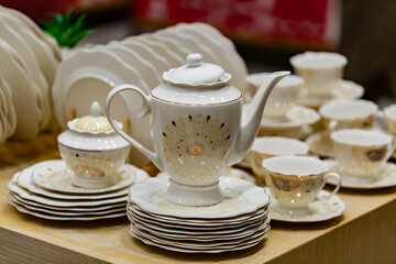 Tea pot and White crockery for tea in shallow depth of field. Cups and saucers on a wooden table. Set cups and teapot in restaurant for event celebration.