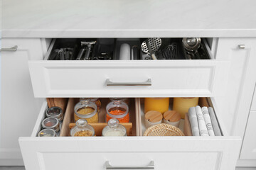 Open drawers with jars and utensils indoors. Order in kitchen