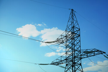 High voltage tower against blue sky on sunny day