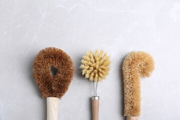 Cleaning brushes for dish washing on grey table, flat lay
