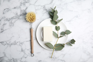 Cleaning supplies for dish washing, plate and eucalyptus branch on white marble table, flat lay