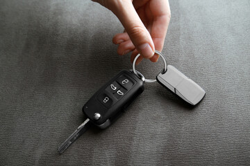 Woman holding car flip key on grey background, closeup