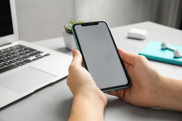 MYKOLAIV, UKRAINE - JULY 10, 2020: Woman holding Iphone 11 with blank screen at table, closeup. Space for design