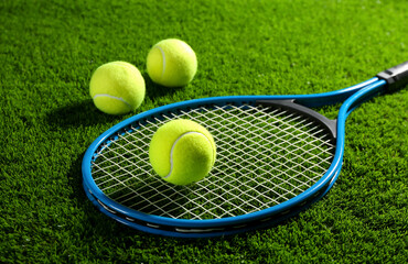 Tennis racket and balls on green grass. Sports equipment